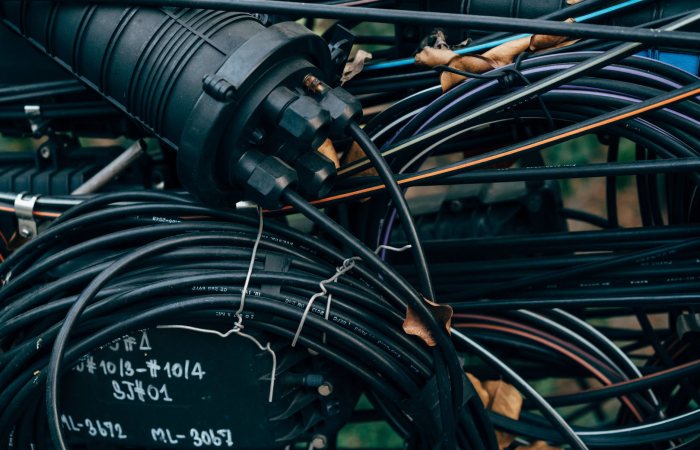 Close-up view of intertwined black cables and connectors in an outdoor telecom setup.