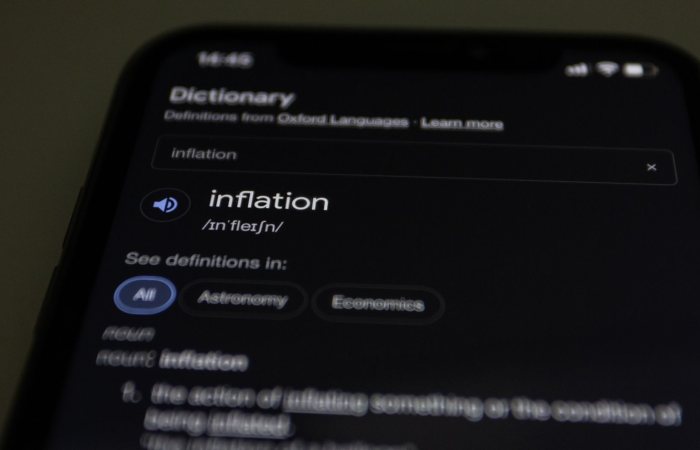 Close-up of a smartphone screen showing the word inflation defined in a dictionary app.