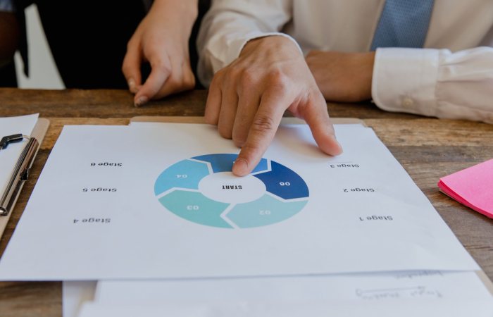 Close-up of hands pointing to a circular business strategy plan on paper.