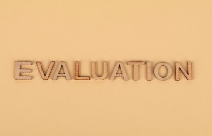 Wooden letter blocks arranged to spell 'evaluation' on a beige background.