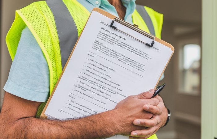 Close-up of home inspector holding a checklist on a clipboard with a pen.
