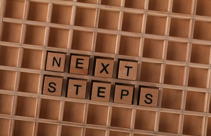 Flat lay of wooden letter blocks spelling 'Next Steps', inspiring progress and motivation.